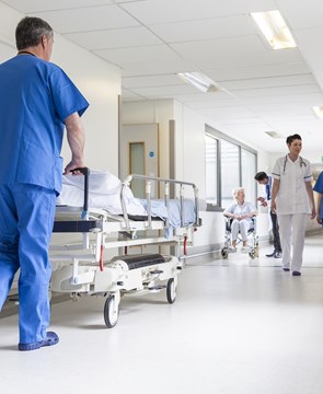Nurse wheeling patient bed down a hospital corridor