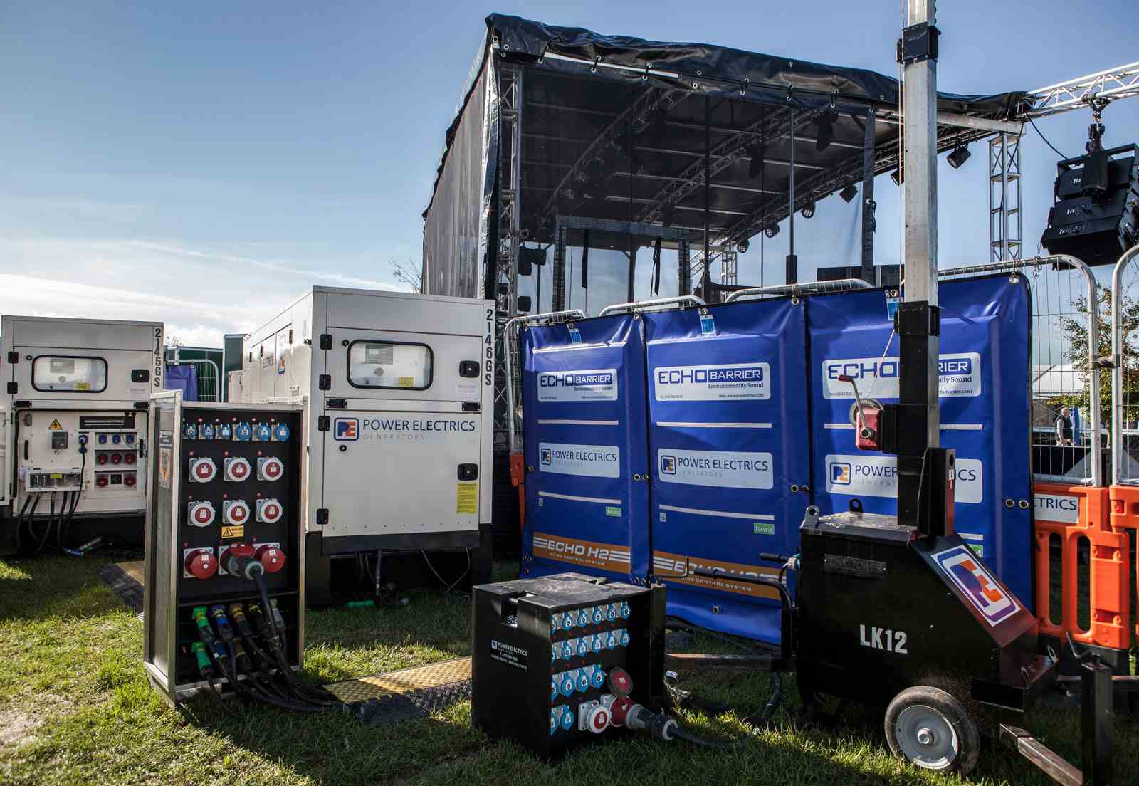Generators, tower light and switch boards behind music festival stage